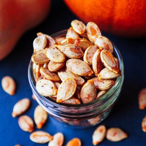 seasoned roasted pumpkin seeds in jar on blue