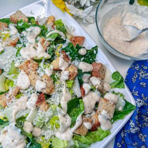caesar salad dressing on salad with dressing next to it
