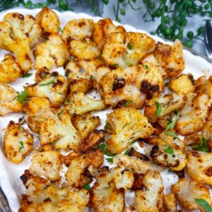 roasted, seasoned cauliflower and parsley pieces on a white platter