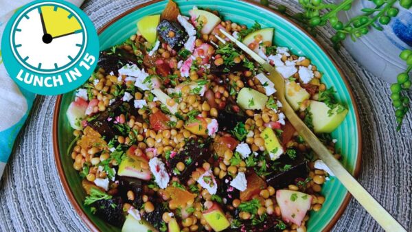green bowl with fork loaded with colourful salad of dark beets, golden lentils, green apple pieces and feta cheese