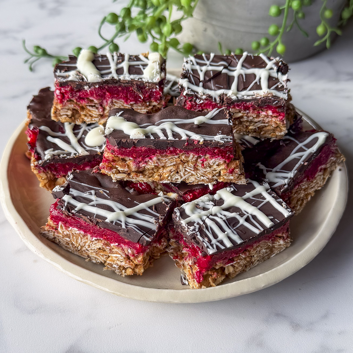 no bake chocolate raspberry oat bars stacked on serving plate