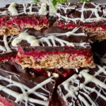 no bake chocolate raspberry oat bars up close showing chocolate, raspberry and oat layers