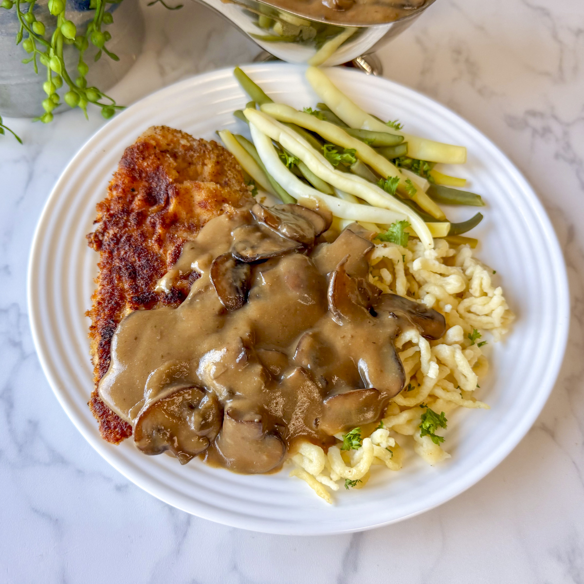 mushroom sauce on schnitzel and spaetzle on white plate with green and wax beans